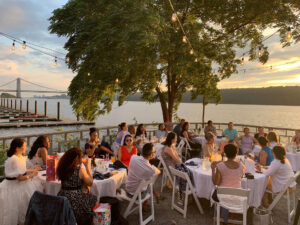 a group of patrons having a private event on the deck of The Hudson's outdoor space as the sun starts to set